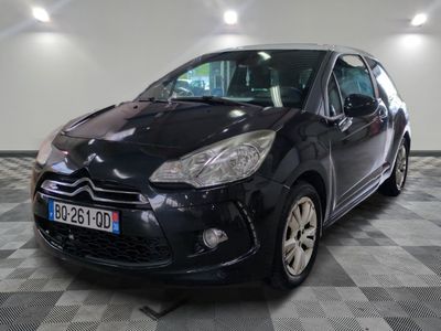 La petite voiture noire est garée dans le garage, sur le sol à damier.