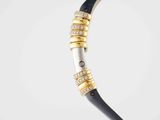 a close up of a black and gold necklace on a white background