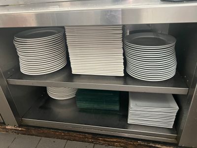 Plusieurs assiettes sont empilées sur une étagère métallique dans une cuisine