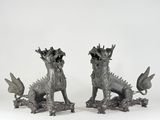 une paire de statues en bronze représentant un dragon et un chien sur fond blanc