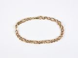 a gold chain bracelet with an oval link on a white background
