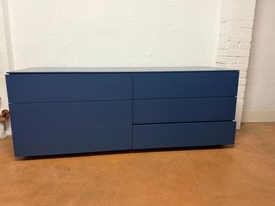 a blue dresser in a room with a white brick wall