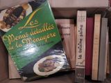 une boîte remplie de livres posée sur une table, à côté d'une pile de livres