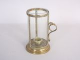 une petite horloge en verre et en laiton posée sur une surface blanche