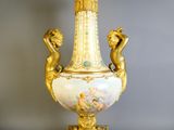 a gold vase with a painting on it sitting on a table
