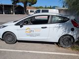 a small white car that is parked in a parking lot