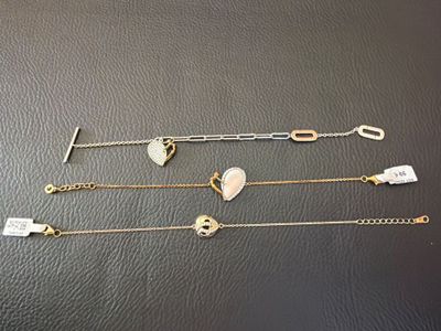 four different bracelets with heart charms on them sitting on a table