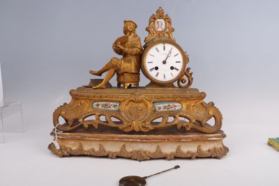 une horloge en or posée sur une table, à côté d'autres objets