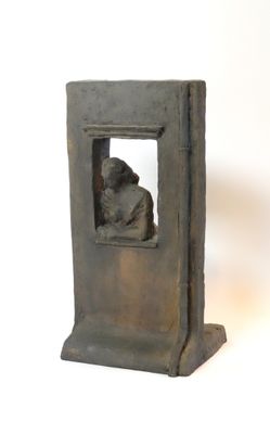 une petite statue représentant un homme assis près d'une fenêtre