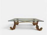 a brass coffee table with a glass top and twisted legs