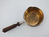 silver plated saucepan with wooden handle on a white surface