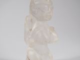 une photo d'une figurine en verre représentant un bébé assis sur une surface blanche