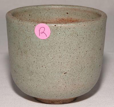une petite tasse avec un autocollant rose dessus