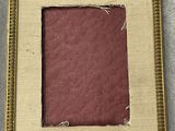 an old picture frame with a red paper in it on a table