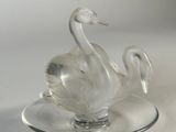 a glass swan on a plate on a white surface
