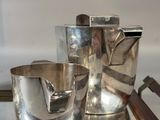 a tray with a silver tea pot and a silver cup on it