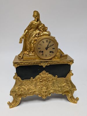 a gold clock sitting on top of a black table