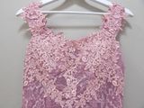 pink lace dress hanging on a hanger on a white wall