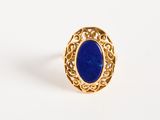 Gros plan sur une bague en or ornée d'une pierre bleue