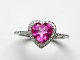 un gros plan d'une bague rose en forme de cœur posée sur une surface blanche