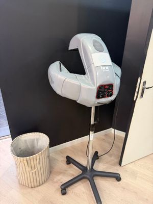 a hair dryer sitting on top of a stand next to a trash can