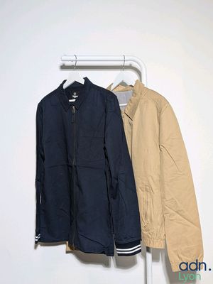 two jackets hanging on a clothes rack in a room