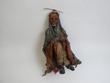 une figurine représentant un homme assis sur une surface blanche