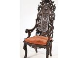 une chaise richement sculptée, dont l'assise est recouverte d'un tissu orange