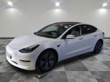 the white tesla model 3 is parked in a large room