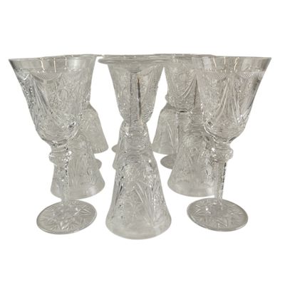 quatre verres à pied en verre transparent sont alignés sur une surface blanche