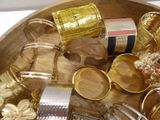 a wooden bowl filled with lots of gold and silver jewelry