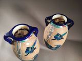 two vases with birds painted on them sitting on a table