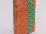 an orange book with a green cover sitting on top of a white surface