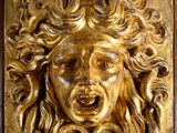 a close up of a gold plaque with a face on it