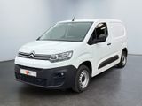La camionnette blanche est garée dans une pièce au sol noir.