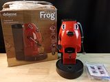 a red coffee maker sitting on a table next to a box