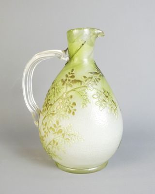a green and white vase with a handle on a table