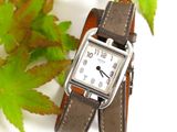 a close up of a wrist watch with a leaf in the background