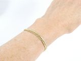 someone is wearing a gold bracelet with a chain on their arm