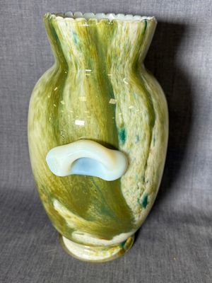 un vase vert avec une anse blanche sur fond gris