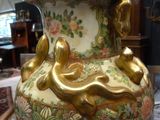 a large vase that is sitting on a table with a lamp on it