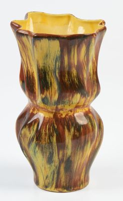 un vase jaune et marron posé sur une surface blanche
