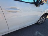 a white car parked in a parking lot with a dog sticking its head out of the window