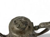 a small metal teapot with a handle on a white surface