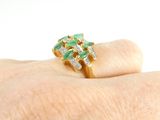 a woman ' s hand holding a green and white diamond ring