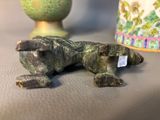 a statue of a dog laying on a table next to a vase
