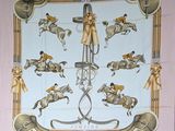 une écharpe rose sur laquelle sont représentés des chevaux et des jockeys
