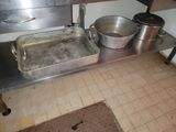 pots and pans sit on a stainless steel shelf in a kitchen