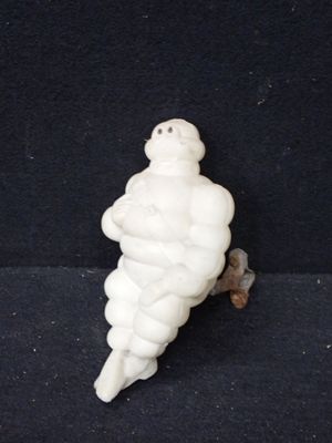 une petite figurine blanche représentant un homme corpulent sur fond noir