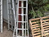 une échelle appuyée contre un immeuble, à côté d'une pile de palettes